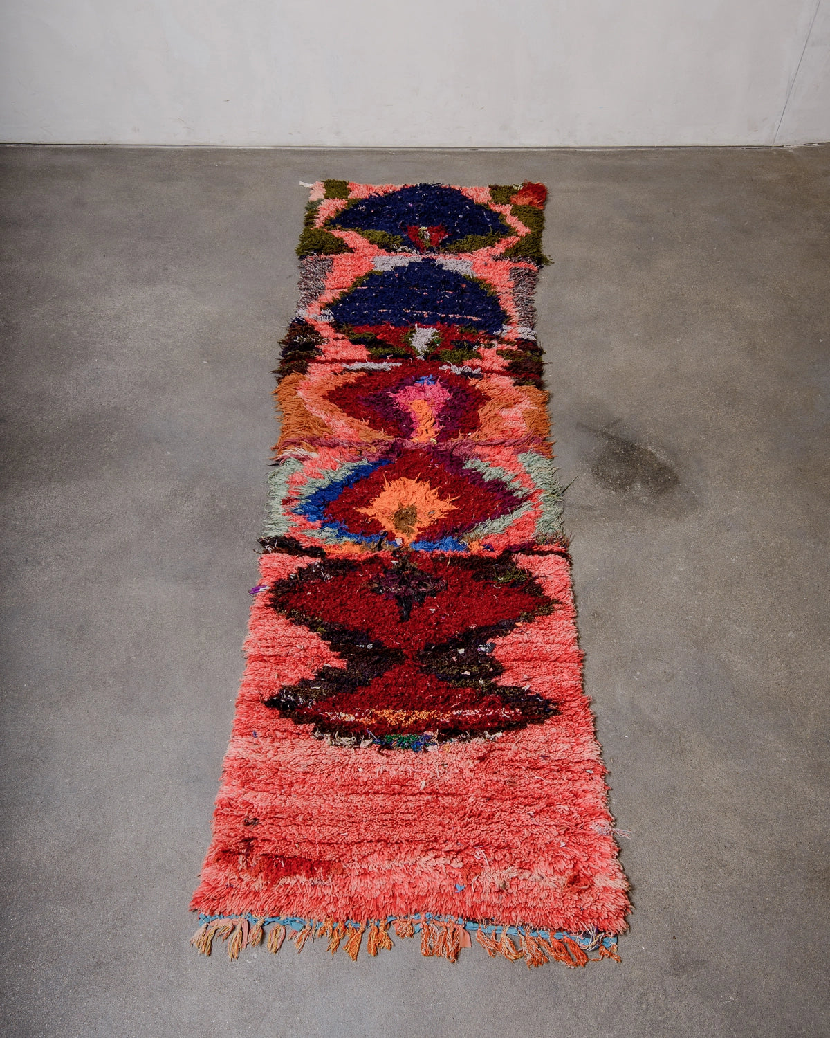 Berberlin Vintage Berber Rug in shades of red, pink, navy, khaki, burgundy photographed on concrete floor.